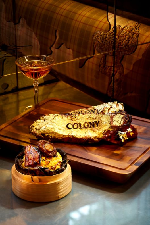 Steak covered in edible gold next to a cocktail.