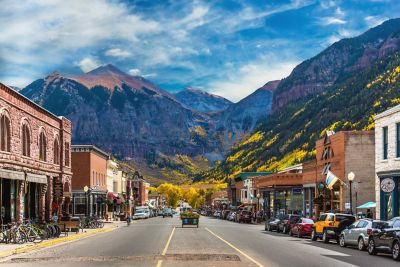 A street lined with low brick buildings and huge mountains in the background