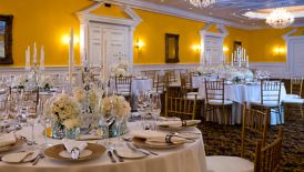 The Banquet Hall set up for a wedding reception and featuring yellow walls, white wainscoting and crystal chandeliers