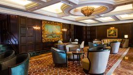 Club Lounge with dark wood-paneled walls, gilt-framed pictures and a white coffered ceiling