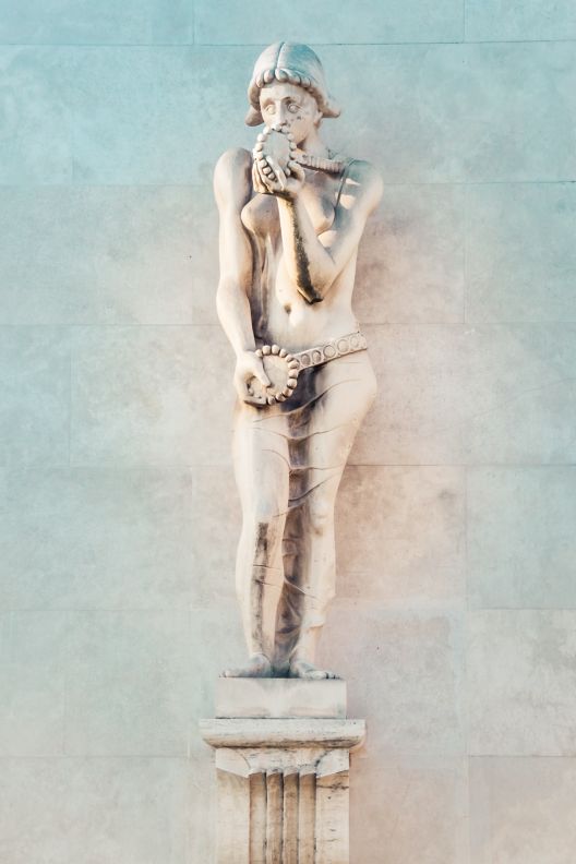 Sculpture of a woman standing on a pillar block.