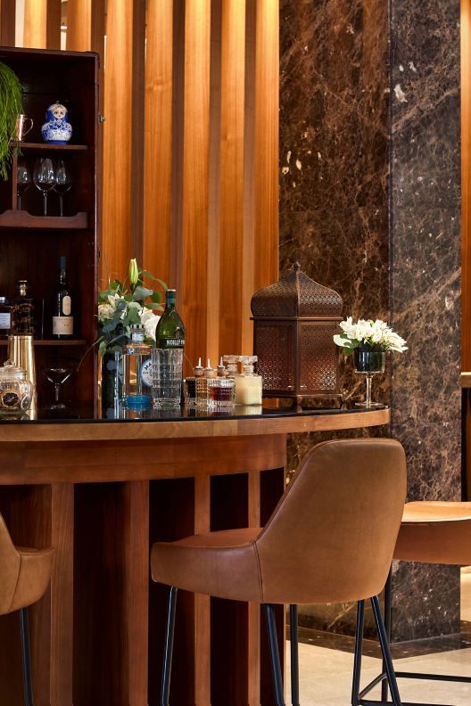 Foyer cocktail bar with stools and liquor displayed among rich wood details.