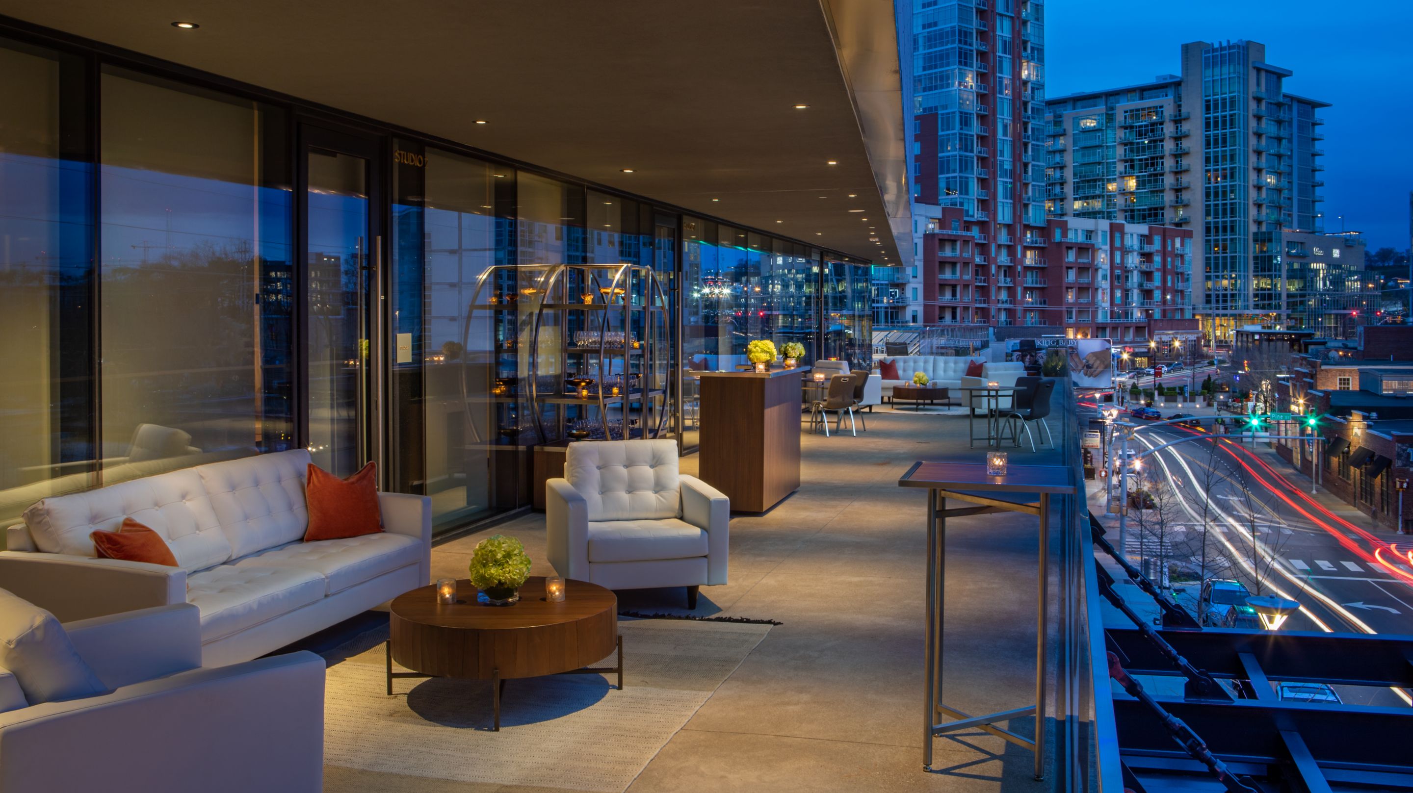 Hotel terrace lounge area with couch and chairs and view of city buildings.