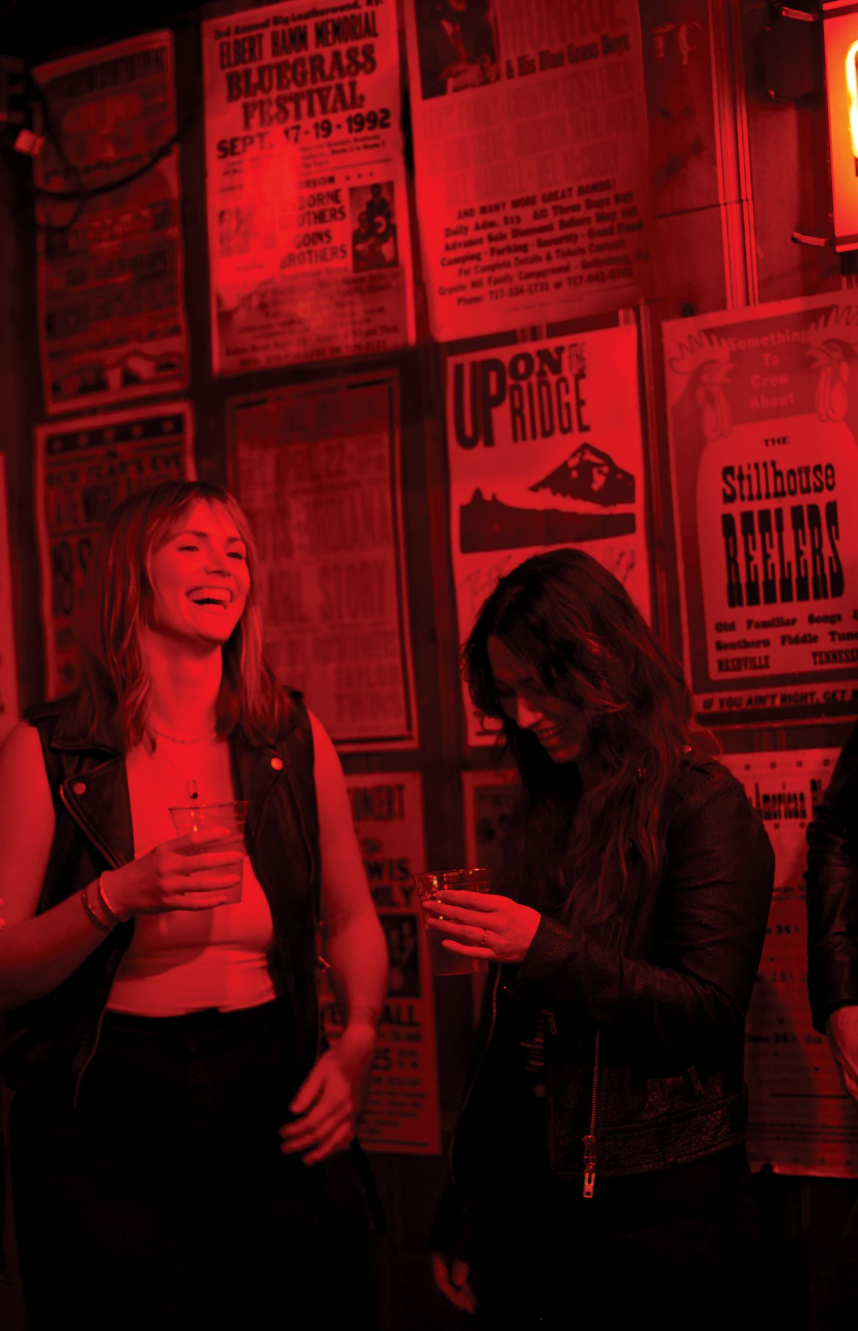 Group hangs out in dark red room with beer. 