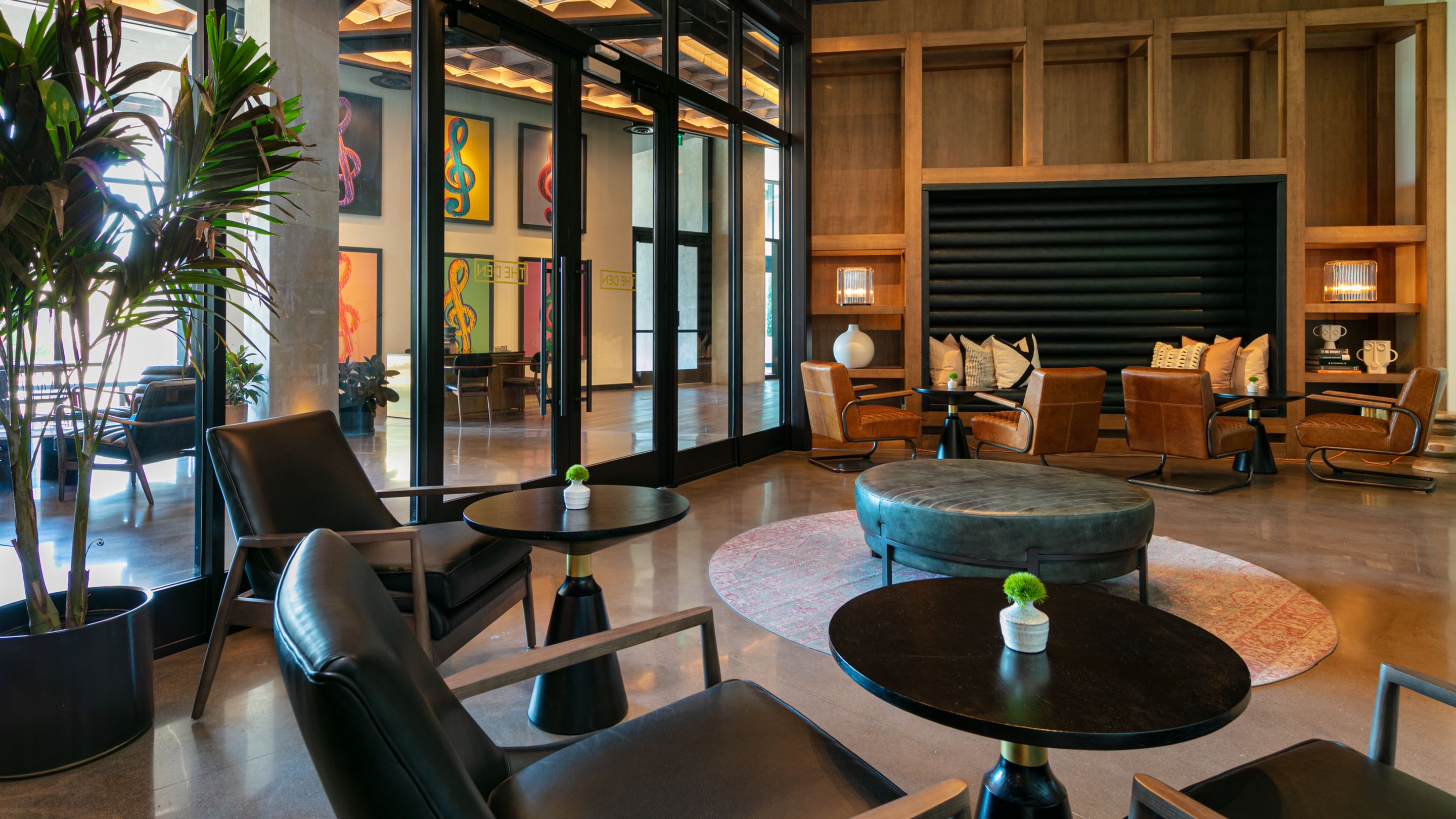 The Den elevated club lounge with leather seats, tables, and floor to ceiling windows. 