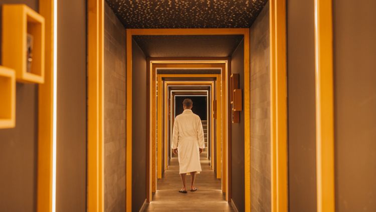 A man walking down a corridor while wearing a robe.