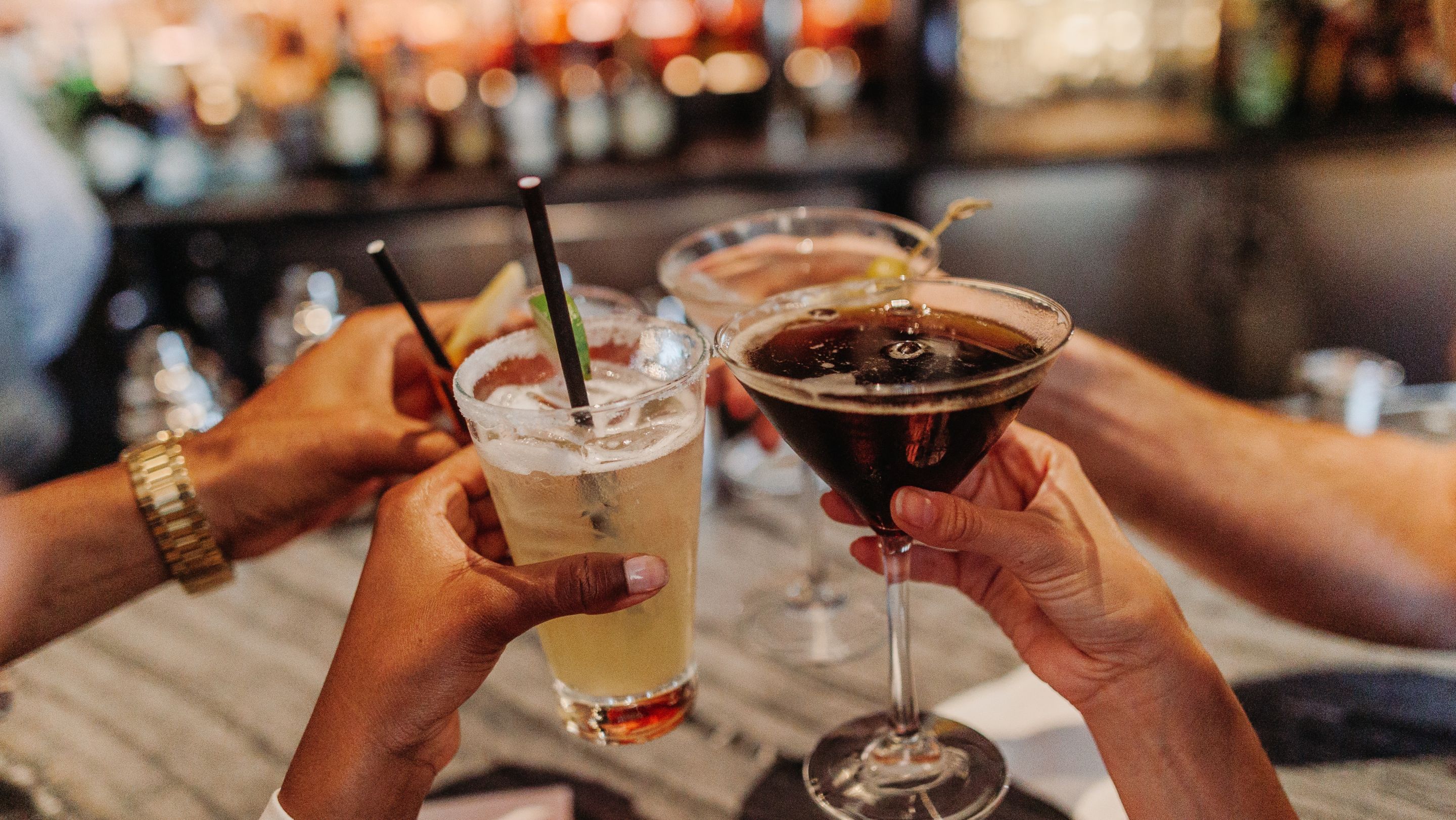 Four people holding their cocktail glasses up together.