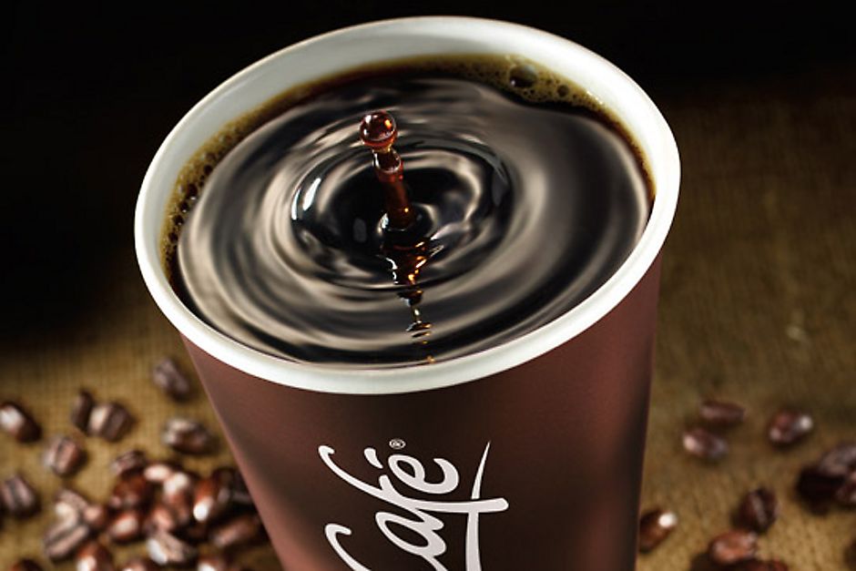 A McCafé Coffee cup surrounded by coffee beans