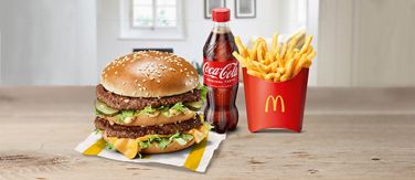 Auf dem Bild sieht man einen Burger, eine Flasche Coca Cola und Pommes Frittes