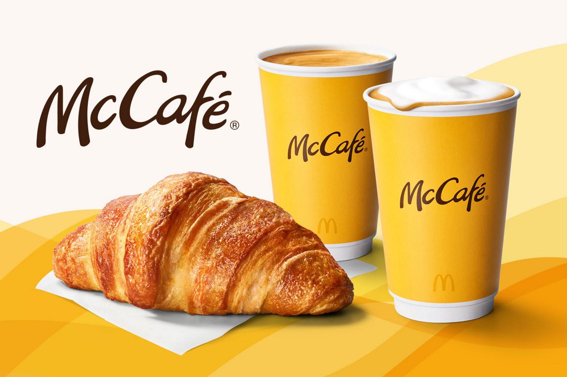McCafé. Wir sehen Kaffee-Spezialitäten und ein Croissant.