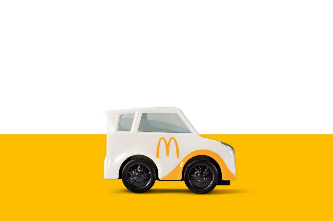 Ein weißes McDelivery Spielzeug-Auto mit gelben McDonald‘s „M“ auf der Seite und gelben Akzenten.