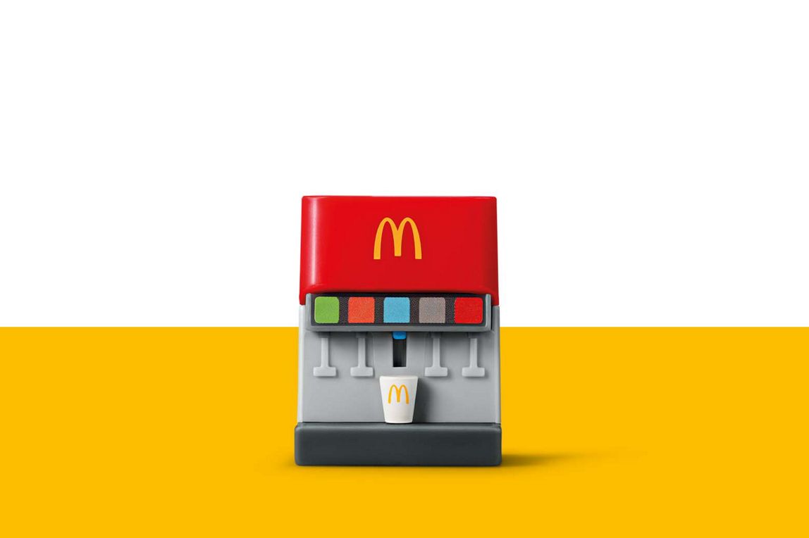 Ein Spielzeug-Getränkespender von McDonald's in Rot und Grau, mit einem kleinen Becher darunter.