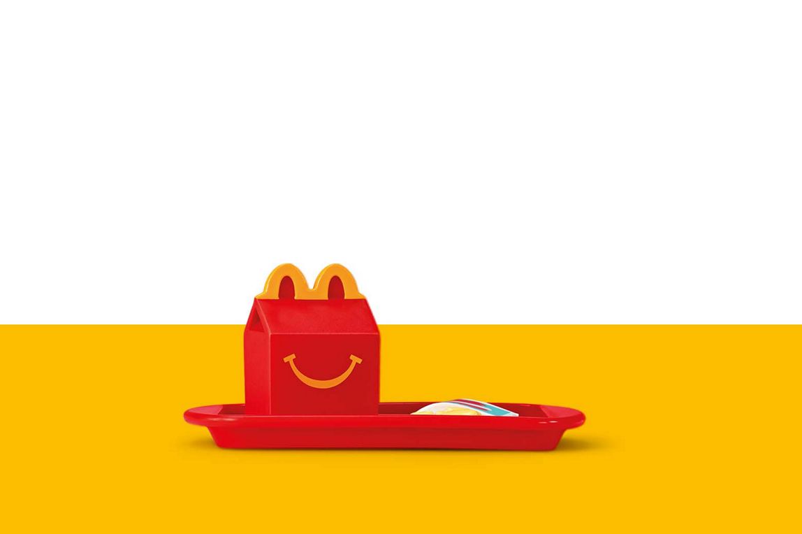 Rote McDonald‘s Happy Meal Box und eine Tüte Apfelstückchen auf einem roten Tablett als Miniatur-Spielzeug.