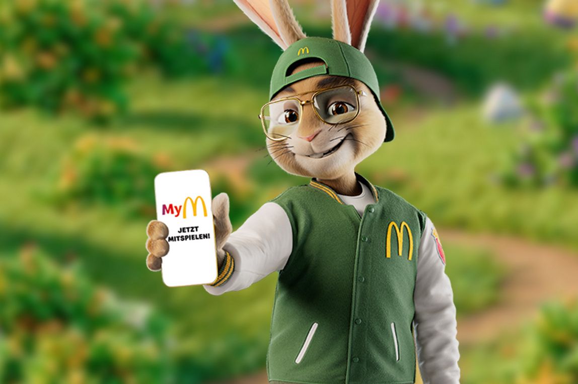 Abbildung: Ein Osterhase zeigt uns sein Handy mit der MyMcDonald’s App auf dem Bildschirm "Jetzt Mitspielen"