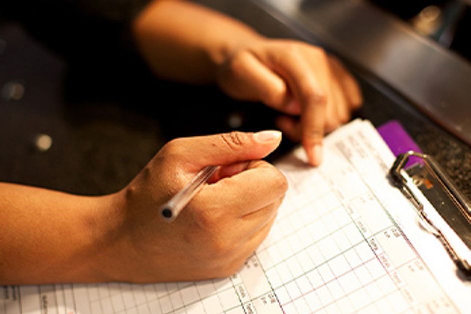 Person mit einem Klemmbrett, die Kontrollberichte einträgt