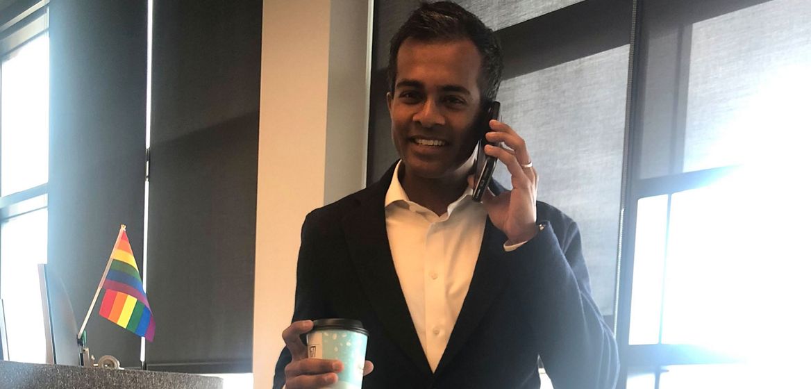 Abiman holding a cup and talking on his cell phone