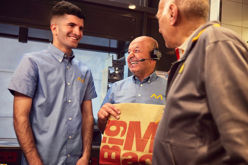 Zwei Führungskräfte von McDonald's begrüßen einen neuen Auszubildenden