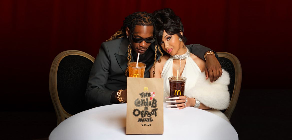 Cardi B & Offset sitting on a table with McDonald's meal 