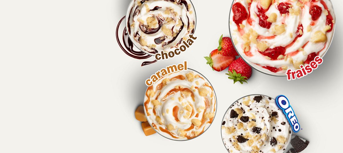 Une vue en plongée de quatre saveurs différentes de McFlurry, comprenant toutes des morceaux de pâte à biscuit à saveur de gâteau au fromage. L’un est accompagné du mot «Chocolat» et contient du sirop de chocolat. L’un est accompagné du mot «Fraises» et contient du sirop de fraise. L’un est accompagné du mot «Caramel» et contient du sirop de caramel. Le dernier est accompagné du mot «Oreo®» et contient des morceaux d’Oreo.