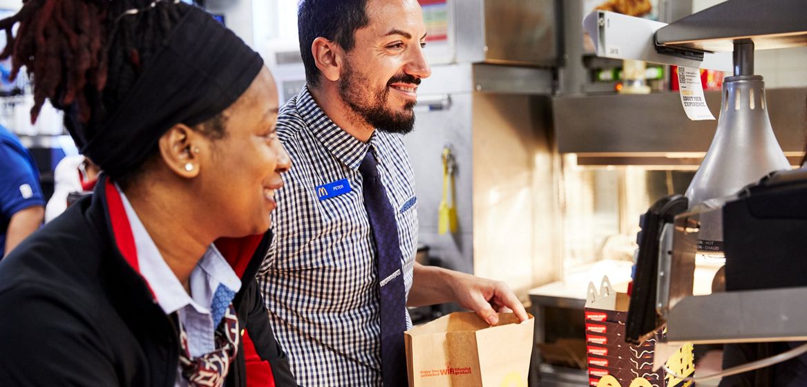 two McDonald's employees in a restaurant smiling and laughing