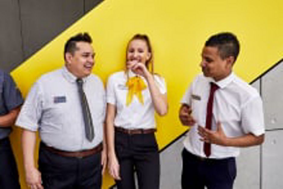 Four McDonald's employees smiling and laughing outside a restaurant