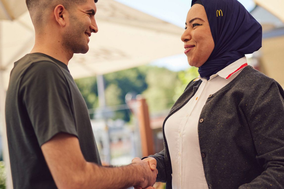 Junger Mann und McDonald’s Mitarbeiterin geben sich die Hand