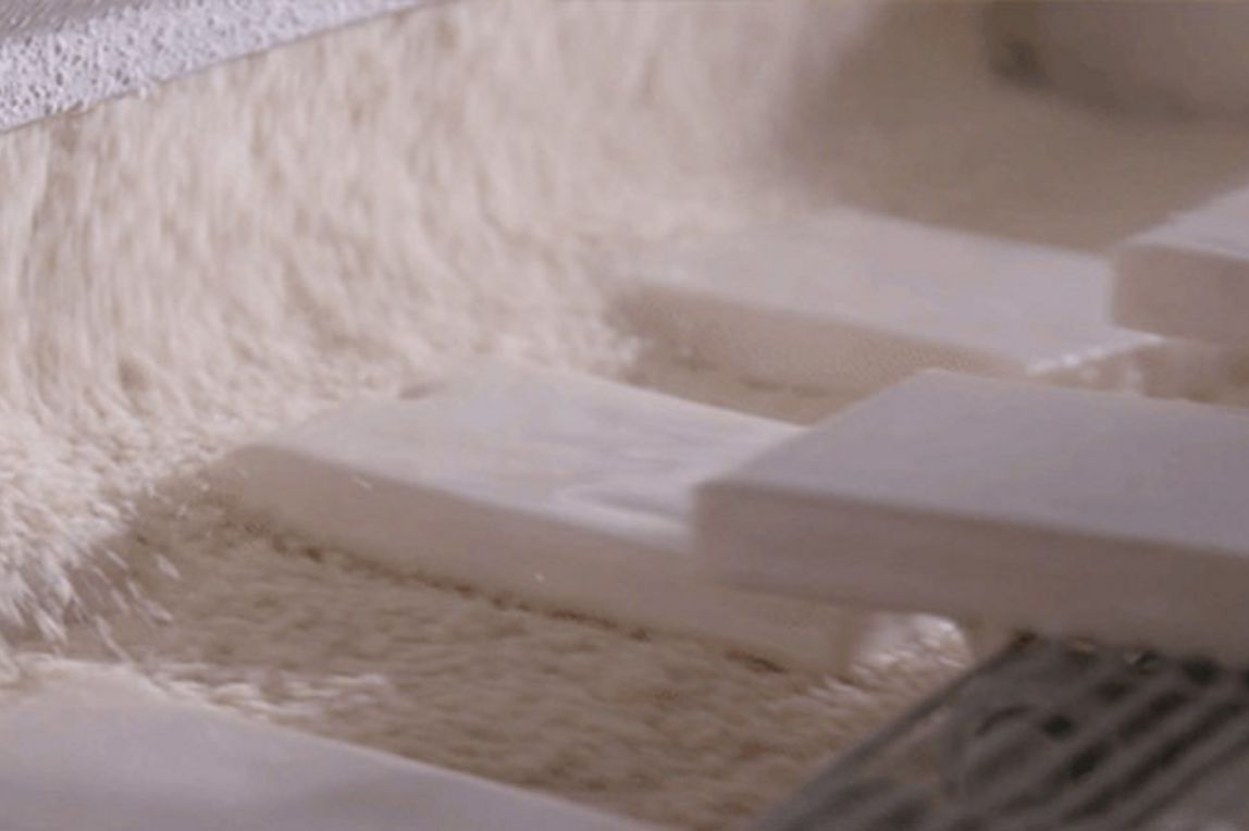 Fisch-Patties, die auf einem Förderband paniert werden.