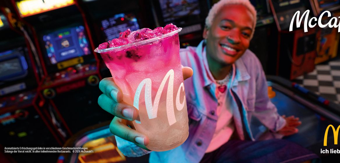 Eine Person hält einen McCafé Pink Dragonfruit Fizzer mit Sprite in der Hand