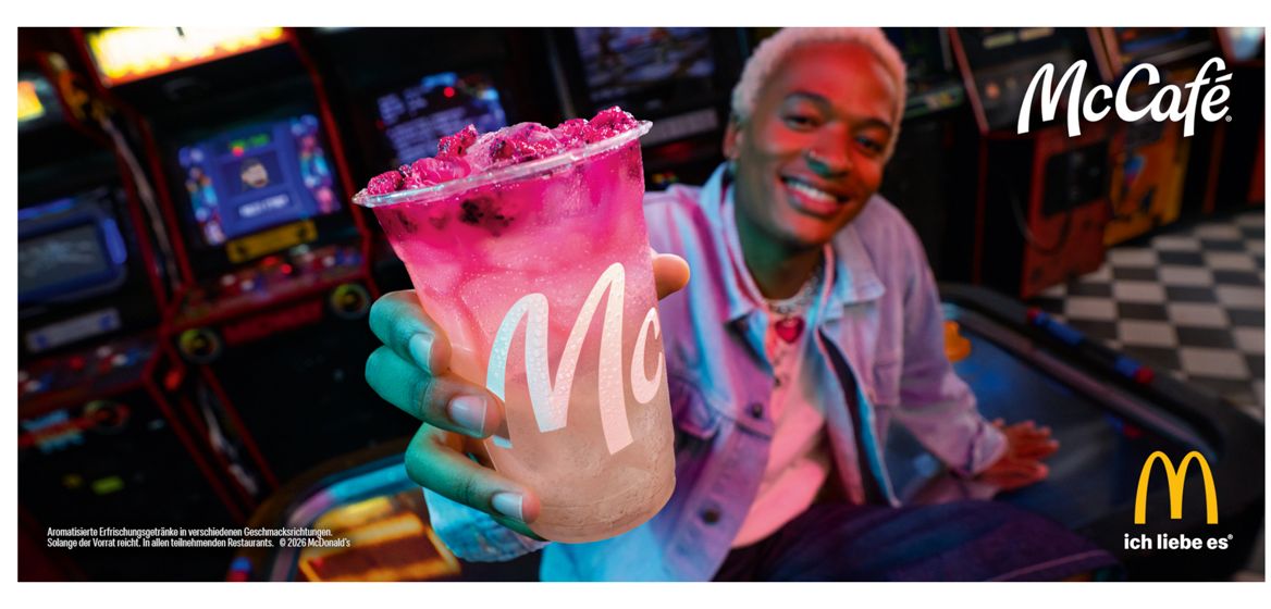 Eine Person hält einen McCafé Pink Dragonfruit Fizzer mit Sprite in der Hand