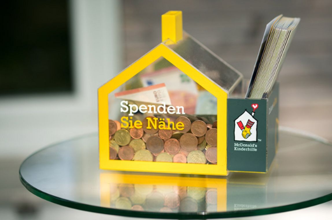 Mit Münzen und Scheinen gefülltes Spendenhäuschen der McDonald's Kinderhilfe