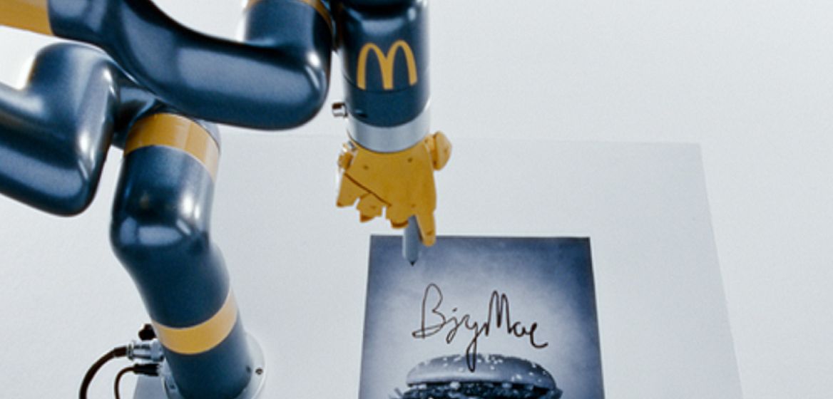 Romotarm med McDonald's logga på sig som skriver autografen Big Mac på en bild av en BigMac.