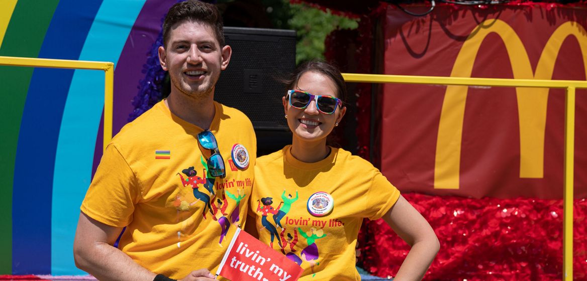 a man and a woman standing in front of a rainbow 