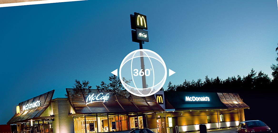 Ein McDonald's Restaurant bei Dämmerung mit einer Illustration in der Mitte, die auf die Möglichkeit eines 360-Grad-Rundgangs verweist