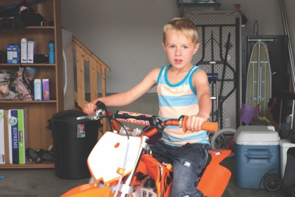Boy siting on an orange dirt bike