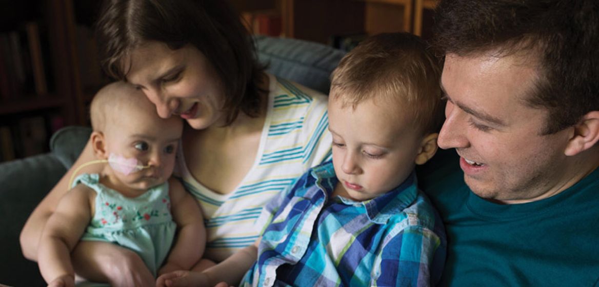 Family of four cuddling and reading a book