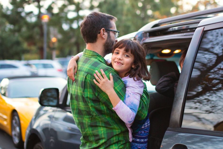 Father carrying daughter into car