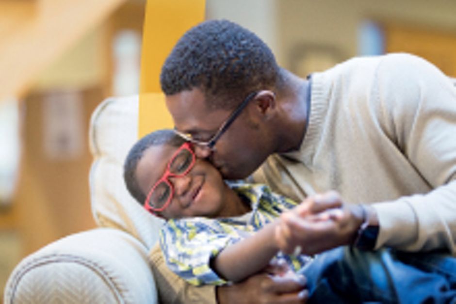 Father giving his son a kiss on the cheek while sitting on a couch