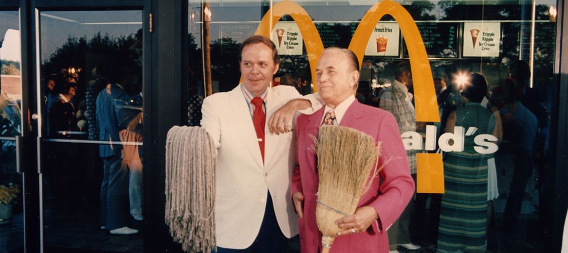 Ray Kroc and Fred Turner pose in front of a McDonald's restaurant 
