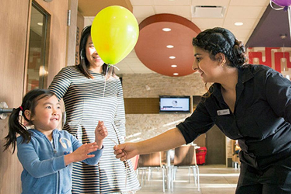 McDonald's staff handing yellow balloon to child and mother