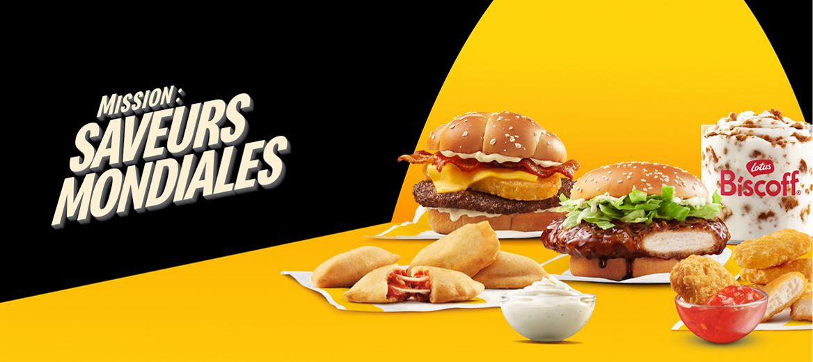 Un faisceau de lumière est projeté sur différents produits du menu Mission : saveurs mondiales de McDonald’s. Il y un hamburger rösti, un sandwich au poulet teriyaki, un McFlurry® Biscoff®, des bouchées de McPizza, et des Poulet McCroquettes avec une sauce de style mayonnaise à l’ail et une sauce chili sucrée épicée. À côté, on voit les mots « Mission : saveurs mondiales ».
