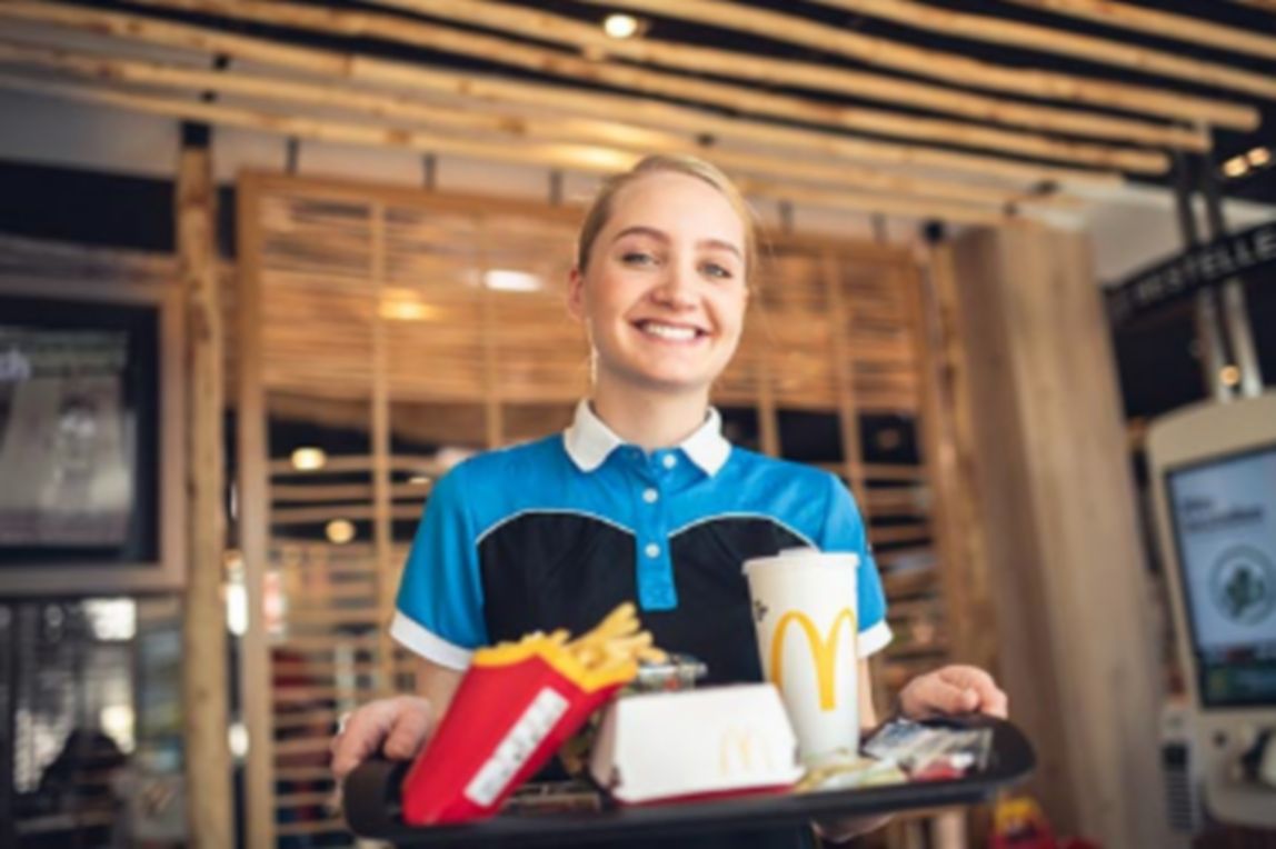 Lächelnde McDonald's Mitarbeiterin mit Tablett in den Händen