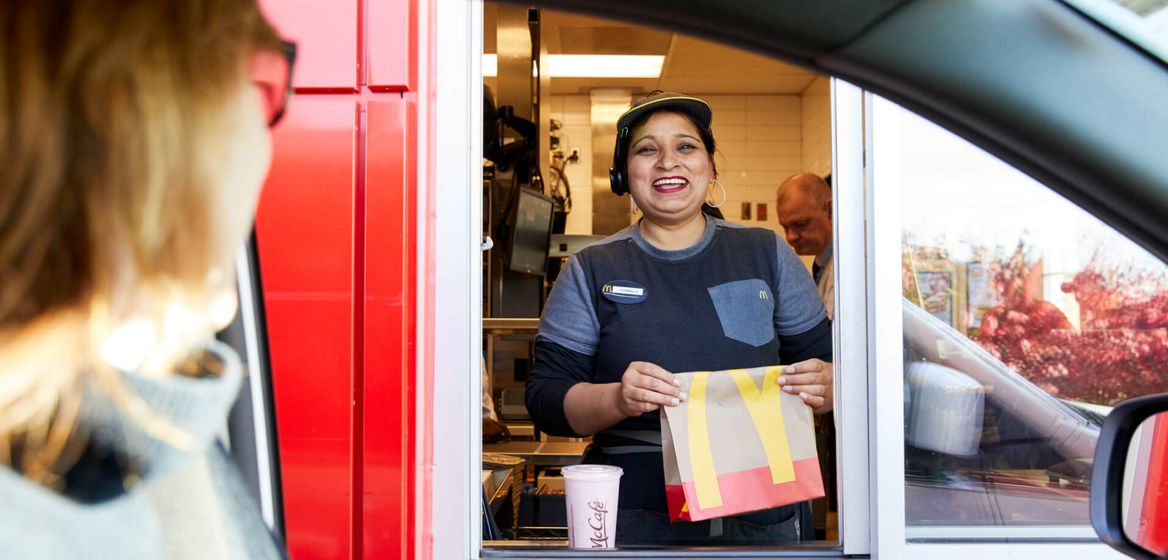 McDonald's employee in Drive Thru window smiling while talking to woman in car