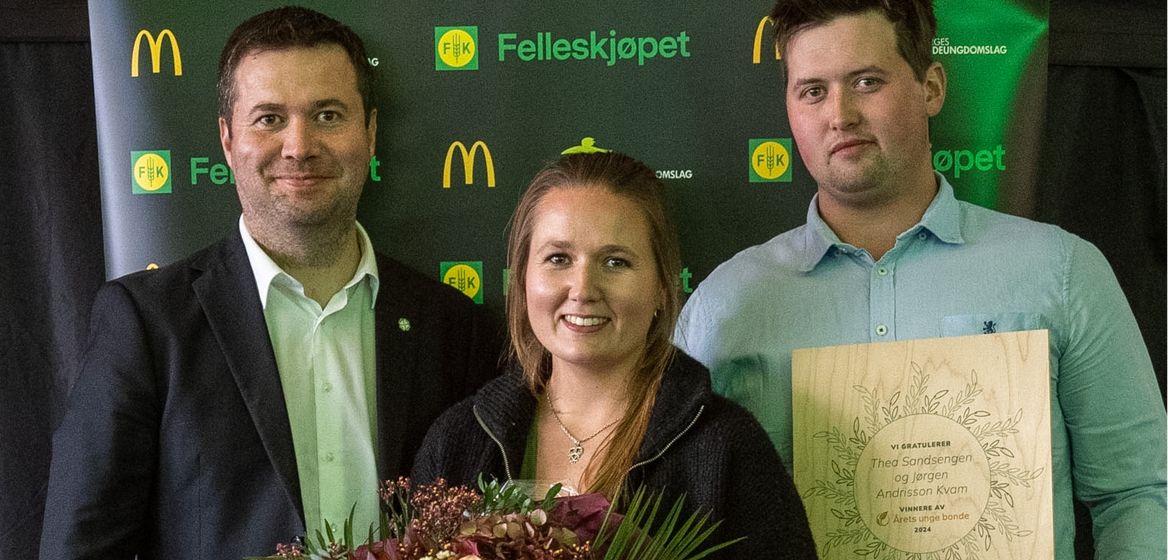 Tre personer står foran en bakgrunn med logoer fra Felleskjøpet, Norges Bygdeungdomslag, og McDonald's. Personen til venstre er en mann i dress, den midterste personen er en kvinne som holder en blomsterbukett, og personen til høyre er en mann som holder en plakat som gratulerer "Theo Sandsengen og Jørgen Andrisson Kvam" som vinnere av prisen "Årets unge bonde 2024". Alle ser mot kameraet og smiler.