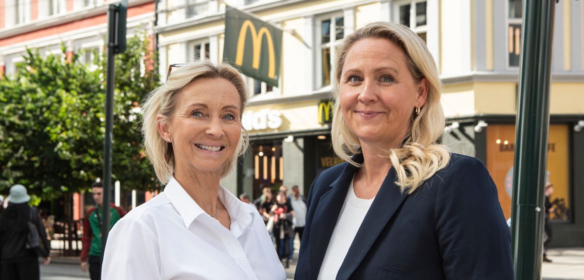 To smilende kvinner står utenfor McD