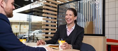 Franchisee speaking with someone while having a coffee in their restaurant.