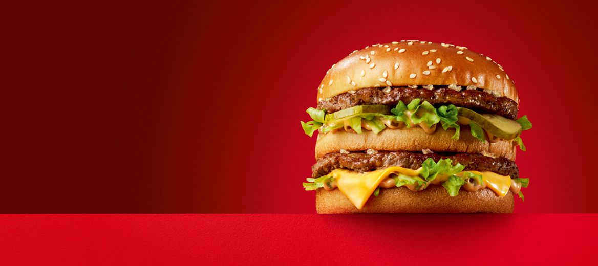 Three burgers on a red plinth and a red background. 