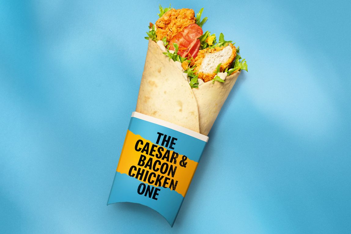 The Caesar & Bacon Chicken One McDonald’s wrap on an orange background.