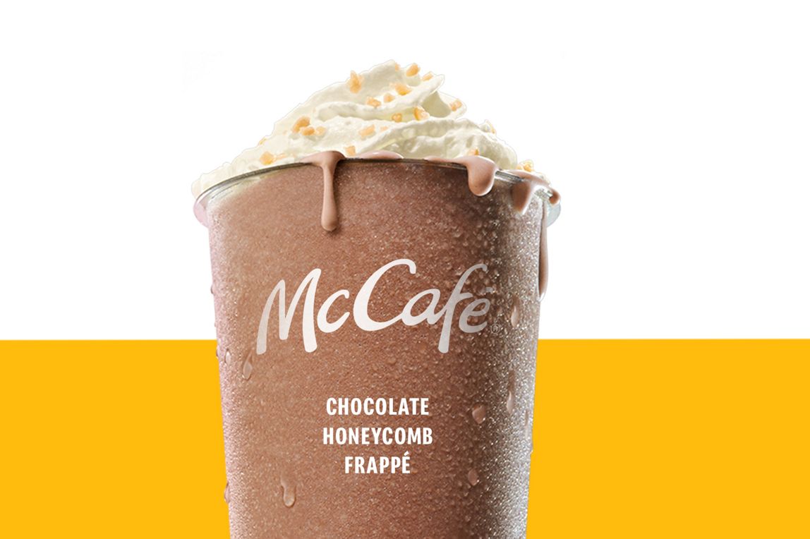 Chocolate Honeycomb Frappe topped with a swirl of whipped cream and honeycomb pieces set against a yellow and white background