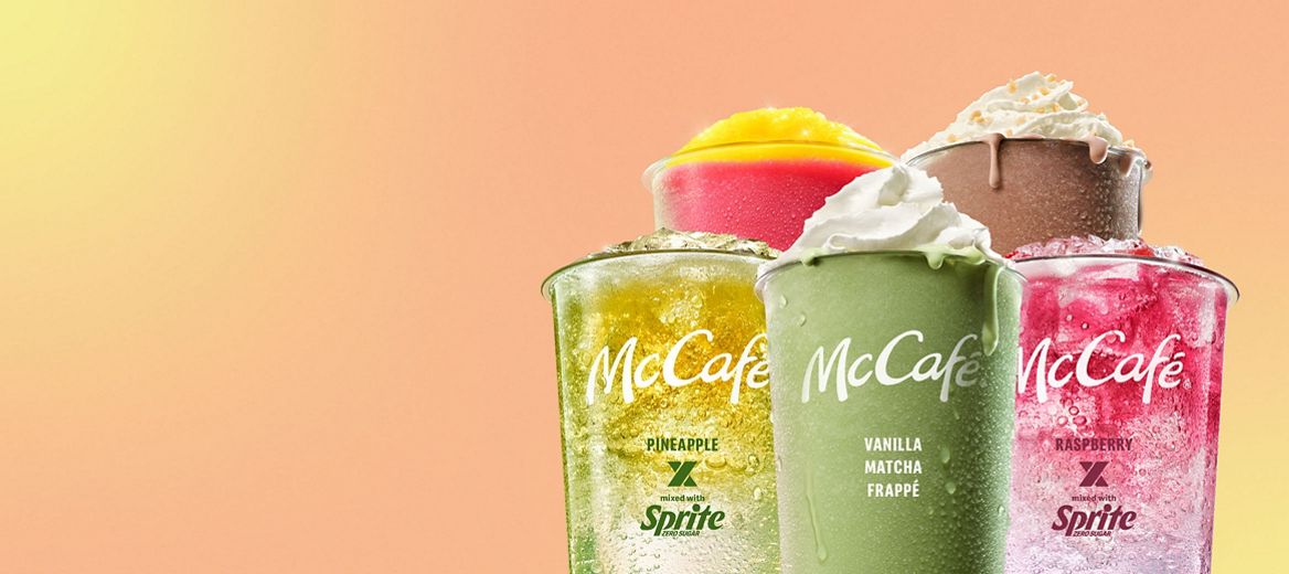 A selection of McCafé cold drinks including a Vanilla Macha Frappe, Chocolate Honeycomb Frappe, Pineapple x Sprite Mixology, Raspberry x Sprite Mixology and Caramel Frappe against a peach and yellow background.