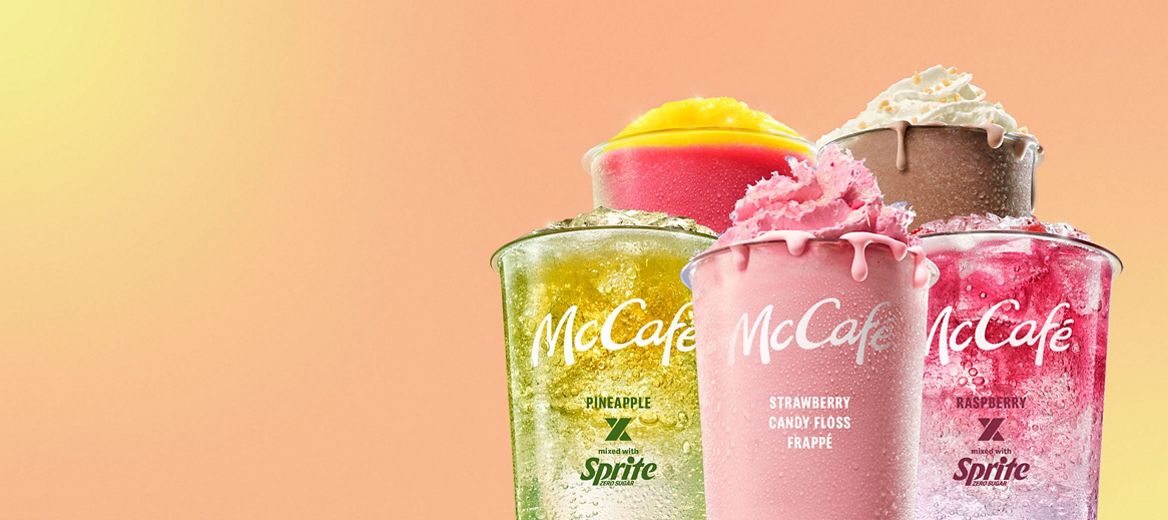 A selection of McCafé cold drinks including a Vanilla Macha Frappe, Chocolate Honeycomb Frappe, Pineapple x Sprite Mixology, Raspberry x Sprite Mixology and Caramel Frappe against a peach and yellow background.